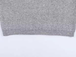 Close-up of grey knit hoodie with tight ribbed hem detail and soft wool texture