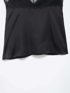 Detailed close-up of a black satin camisole top featuring exquisite lace trim detail
