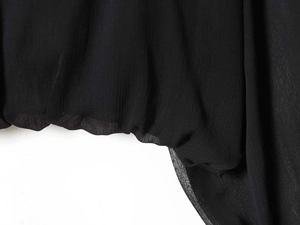 Close-up of semi-transparent black chiffon shirt fabric with vertical pleated texture
