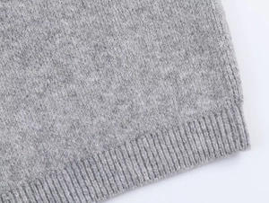 Close-up of light grey knitted hoodie fabric with ribbed hem detail and soft texture