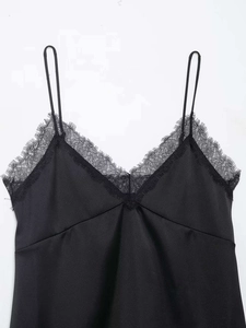 Detail of black satin camisole with delicate eyelash lace trim on V-neckline