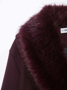 Detailed close-up of dark wine red wool coat featuring a plush faux fox fur collar and neck label