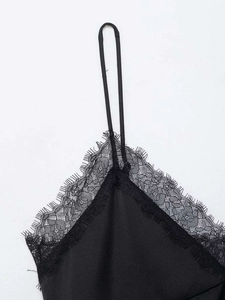 Detailed macro view of black satin camisole with delicate eyelash lace trim at the neckline