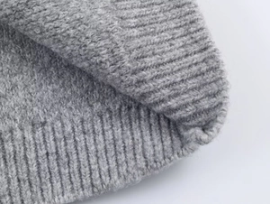 Detail of grey knitted fabric texture and ribbed hem on a loose casual hooded jacket