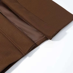 Gros plan sur un manteau en laine marron foncé montrant les coutures et la doublure satin