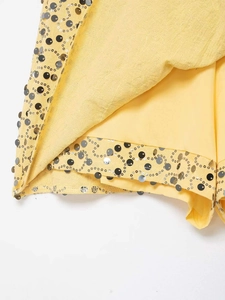 Detail of yellow mini skirt featuring dense silver and dark grey sequins with smooth lining