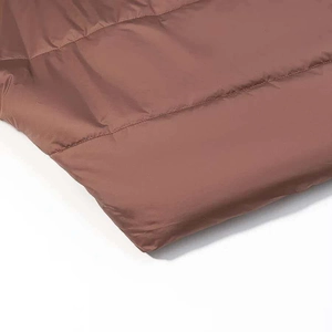 Detailed macro view of chocolate brown quilted winter jacket fabric with glossy finish