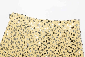Close-up of ginger yellow mini skirt with black and silver sequins in wave patterns