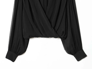 Detail of elegant black wrap-style blouse with gathered neckline and buttoned cuffs