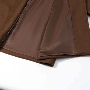 Détail d'un manteau en laine marron foncé montrant l'ourlet et la doublure en satin