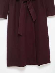 Detailed view of the dark burgundy wool coat with a matching waist tie belt and hem