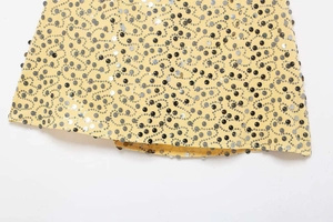 Close-up of yellow sequin mini skirt featuring silver and black heart-shaped embroidery