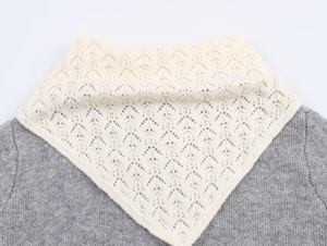 Detail of off-white hollow knit faux collar with scalloped lace edges on a grey sweater