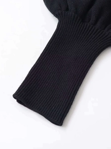 Nahaufnahme der gerippten Manschetten am schwarzen Strickpullover mit Puffärmeln
