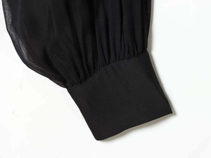 Detail of sheer black pleated chiffon sleeve with wide cuff and premium stitching
