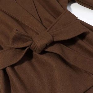 Gros plan d'un manteau en laine marron avec ceinture nouée et texture de tissu élégante