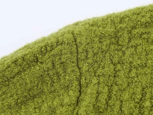 Detailed macro view of the grass green knit sweater fabric texture and soft wool fibers