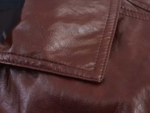 Detail view of double stitching and textured brown faux leather on a biker jacket