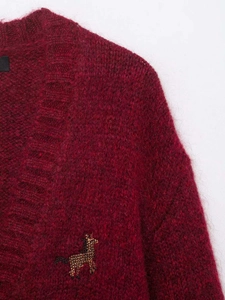 Detail of burgundy mohair cardigan with golden animal embroidery and fluffy texture