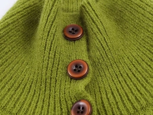 Detail of green knit cardigan with textured vertical stripes and brown buttons
