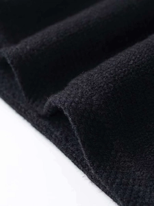 Nahaufnahme von schwarzem Strickstoff mit dicker Textur und weichem Puffärmel-Detail