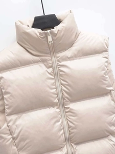 Détail d'un gilet matelassé beige clair avec col montant et fermeture éclair en métal