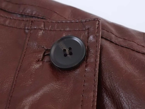 Close-up of brown faux leather jacket texture with a black round four-hole button detail