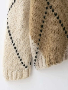 Détail du tricot épais montrant les motifs de losanges et les poignets côtelés