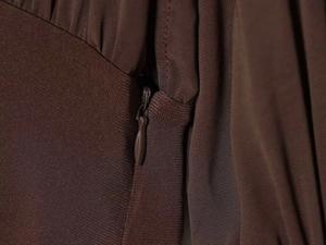 Detail of invisible zipper closure and textured fabric on brown long sleeve dress