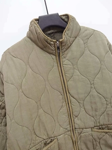 Detail of olive green quilted jacket featuring onion stitching and metal zipper