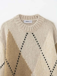Gros plan détaillé d'un pull en maille vintage avec motifs losanges et étiquette de marque