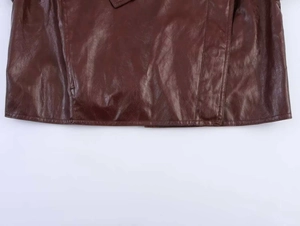 Close-up of the hemline and stitching detail on a vintage dark brown faux leather jacket