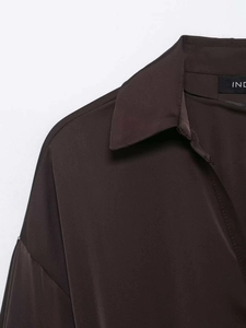 Détail du col classique et du tissu satiné lisse sur une blouse marron foncé