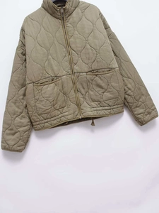 Close-up of olive green quilted jacket featuring onion stitch pattern and large pockets