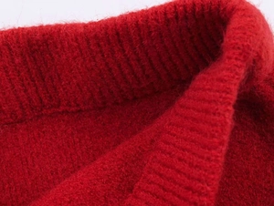 Close-up of red ruffled knitwear showing fine ribbed texture and soft fabric detail