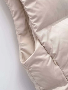 Détail de la poche zippée invisible et de la texture matelassée du gilet beige
