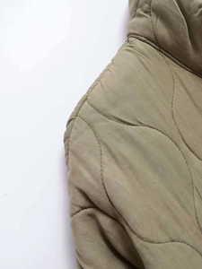 Detail of onion-quilted khaki jacket showing stitching and twill fabric texture