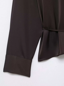 Détail de la chemise en satin chocolat avec texture lisse et détail de taille ceinturée