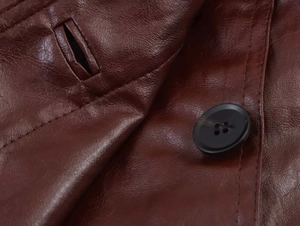 Close-up of a black button and fine stitching on dark red brown leather biker jacket