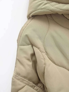Detail shot of khaki wave-quilted jacket showing precise stitching and smooth fabric texture