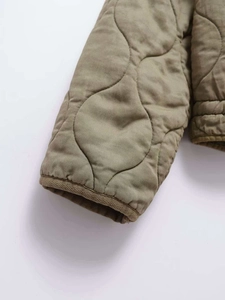 Close-up of olive green quilted jacket cuffs featuring premium wave stitching detail