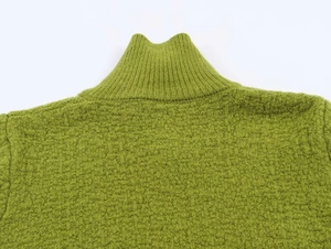 Close-up of grass green knit sweater featuring ribbed high collar and textured fabric