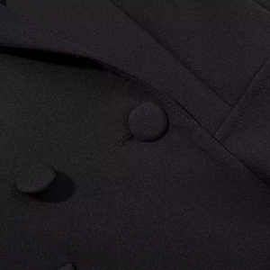 Detailed close-up of woven fabric and black fabric-covered buttons on an elegant dress