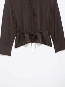 Détail d'une chemise en satin marron foncé avec cordon de serrage et texture soyeuse