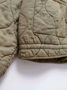 Detail of onion quilted jacket with ribbed elastic hem and khaki twill fabric texture
