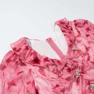 Detail of pink floral dress featuring V-neck ruffle trim and invisible zipper on back