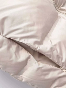 Vue macro du gilet matelassé beige montrant la texture du tissu et le détail du zip invisible