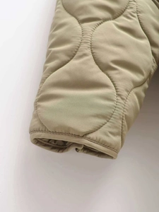 Macro view showing onion-style wavy quilting on olive green padded jacket sleeve