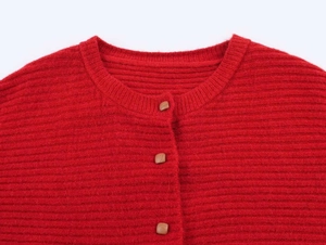 Close-up of red ruffled knit cardigan collar with textured weave and brown square buttons