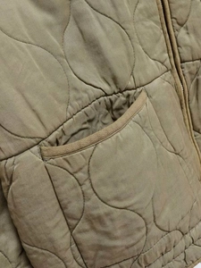 Macro shot of olive quilted jacket fabric with onion stitching and zipper pocket detail